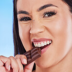 Chocolate, happy and portrait of woman in studio eating luxury, sweet treats and candy on blue background. Sugar, unhealthy diet and face of female person with cocoa bar, dessert and delicious snack