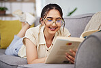 Happy woman, reading and book on sofa in home for story, novel and studying literature. Young student, gen z girl and relax with books in lounge for learning, knowledge and education in living room