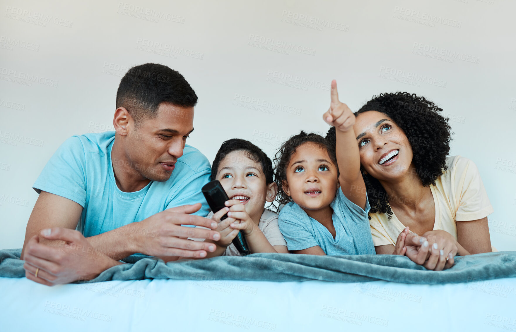 Buy stock photo Father, mom and kids on bed, watching tv and smile for comedy, funny movie or pointing in family home. Happy parents, children and watch television show with streaming, subscription or laugh together