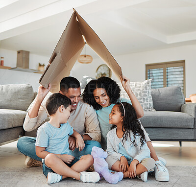 Buy stock photo Happy family, children and parents with home insurance, investment and safety or love on floor with mother and father. Kids and interracial people with cardboard roof for house cover and security