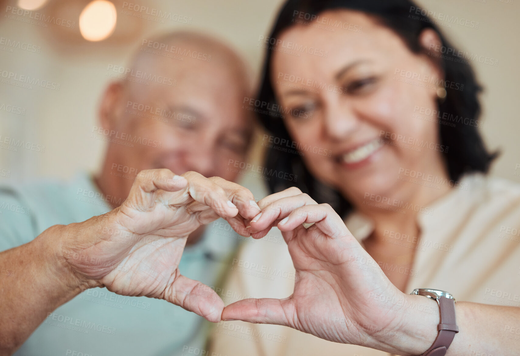 Buy stock photo Hands, heart and love with a senior couple in their home for health, wellness or trust during retirement. Emoji, shape or hand gesture with an elderly man and woman closeup in their house together