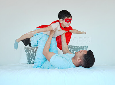 Buy stock photo Airplane, bedroom and dad playing with his kid for bonding, fun or happiness at their home. Happy, smile and young father relaxing with his boy child in a superhero costume on the bed at family house