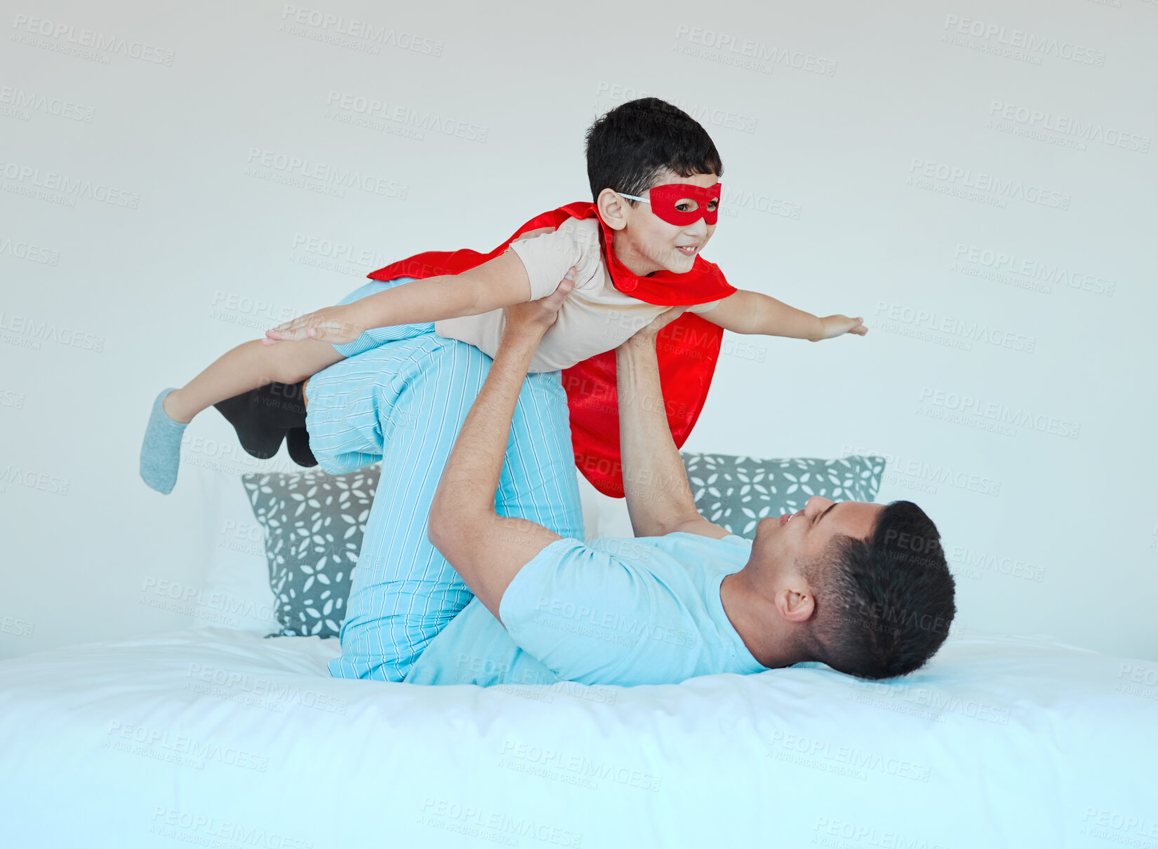 Buy stock photo Airplane, bedroom and dad playing with his kid for bonding, fun or happiness at their home. Happy, smile and young father relaxing with his boy child in a superhero costume on the bed at family house