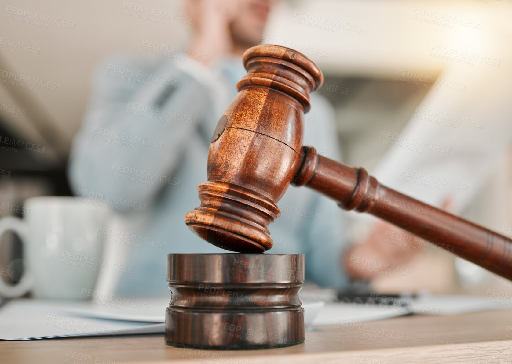 Buy stock photo Closeup, gavel and law on table, office and attorney man in blurred background with phone call for networking. Advocate, lawyer or judge with legal hammer, paperwork or documents for court evidence