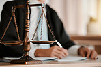 Closeup, scales and law on table, office and attorney man in blurred background with reading for crime analysis. Advocate, lawyer or judge with legal hammer, paperwork or documents for court evidence