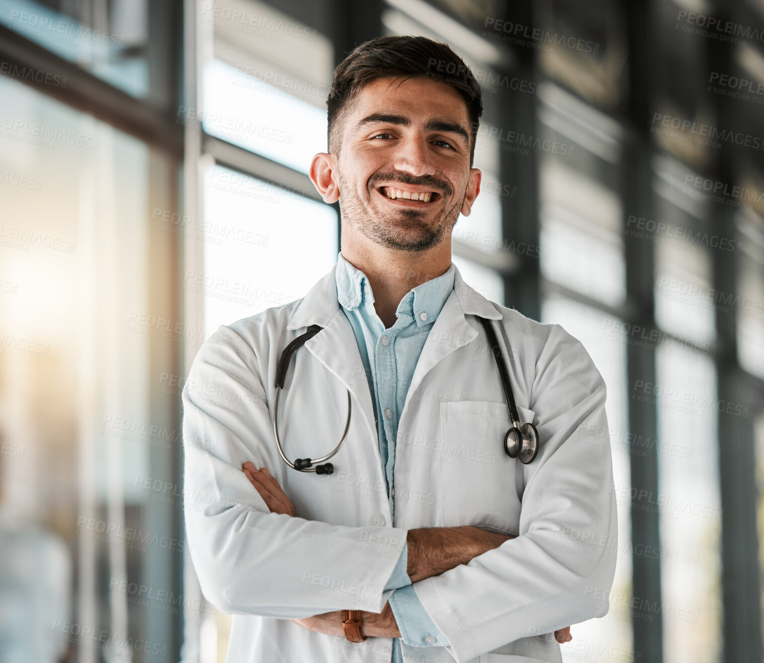 Buy stock photo Crossed arms, confidence and portrait of a male doctor with a stethoscope in a medical hospital. Happy, smile and headshot of a professional young man healthcare worker or surgeon in medicare clinic.