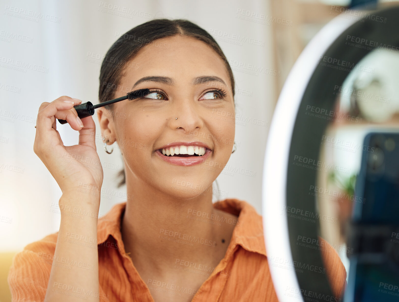 Buy stock photo Smile, house and a woman with makeup and a phone for influencer review, social media or blog. Thinking, happy and a young girl with mascara or cosmetics and mobile lighting for live streaming vlog