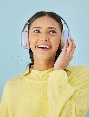 Buy stock photo Woman with smile, headphones and mockup in studio for podcast, mobile app and streaming radio site. Sound, music subscription and happy girl listening to audio on earphones on blue background space.