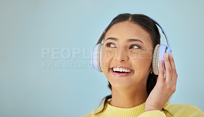 Buy stock photo Woman with smile, headphones and mockup in studio thinking with technology on mobile app and streaming radio site. Podcast, music media subscription and happy girl with sound on blue background space