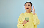 Happy woman with phone, headphones and banner mockup in studio on social media, mobile app and streaming radio. Smile, relax and music media subscription, girl with cellphone on blue background space