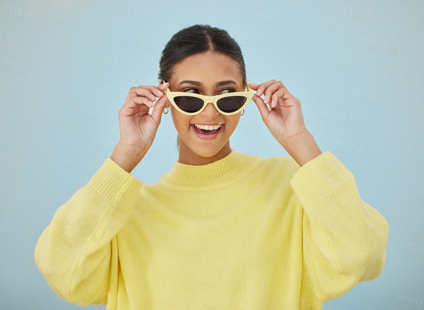 Buy stock photo Happy, sunglasses and young woman in a studio with a casual, stylish and cool sweater outfit. Happiness, smile and female model with trendy style and fashion accessory isolated by a blue background.