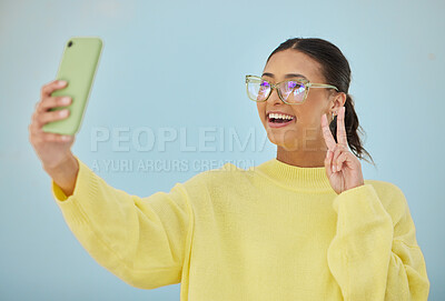 Buy stock photo Selfie, peace sign and happy studio woman with emoji v sign, icon and pose for social network, memory picture or photography. Gen z person, youth or influencer post to media app on blue background