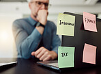 Insurance, tax and finance on sticky notes in an office with a business man at his desk feeling stress or anxiety. Laptop, accounting or audit with a male employee worried while working on a computer