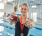 Swimming woman, trophy and sports with finger, smile and pride for success, goals and achievement by pool. Girl, athlete or champion with gold medal, number one icon and happy for winning performance