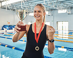 Swimming, woman and winner in competition with medal and trophy, achievement or happiness from success in the race or pool. Winning, celebration and athlete or swimmer on podium with gold award