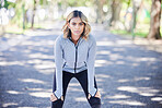 Fitness, exercise and portrait of a woman outdoor at a park with commitment and focus on wellness. Young female person on a road in nature for a break or rest after workout, running or training