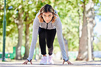 Run, exercise and a woman in start position outdoor at a park with commitment and focus on wellness. Young female person on a road in nature ready for workout, running or training for marathon