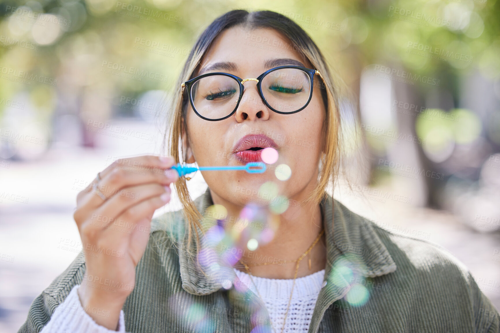 Buy stock photo Face of woman blowing bubbles in park, garden and freedom for fun, good mood and carefree personality. Happy, young and female gen z girl with soap bubble wand outdoor to relax on summer holiday 