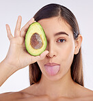 Face, skincare and woman with avocado, tongue out and isolated on a white background in studio. Portrait, beauty and natural model with fruit food for nutrition, healthy diet or omega 3 for wellness