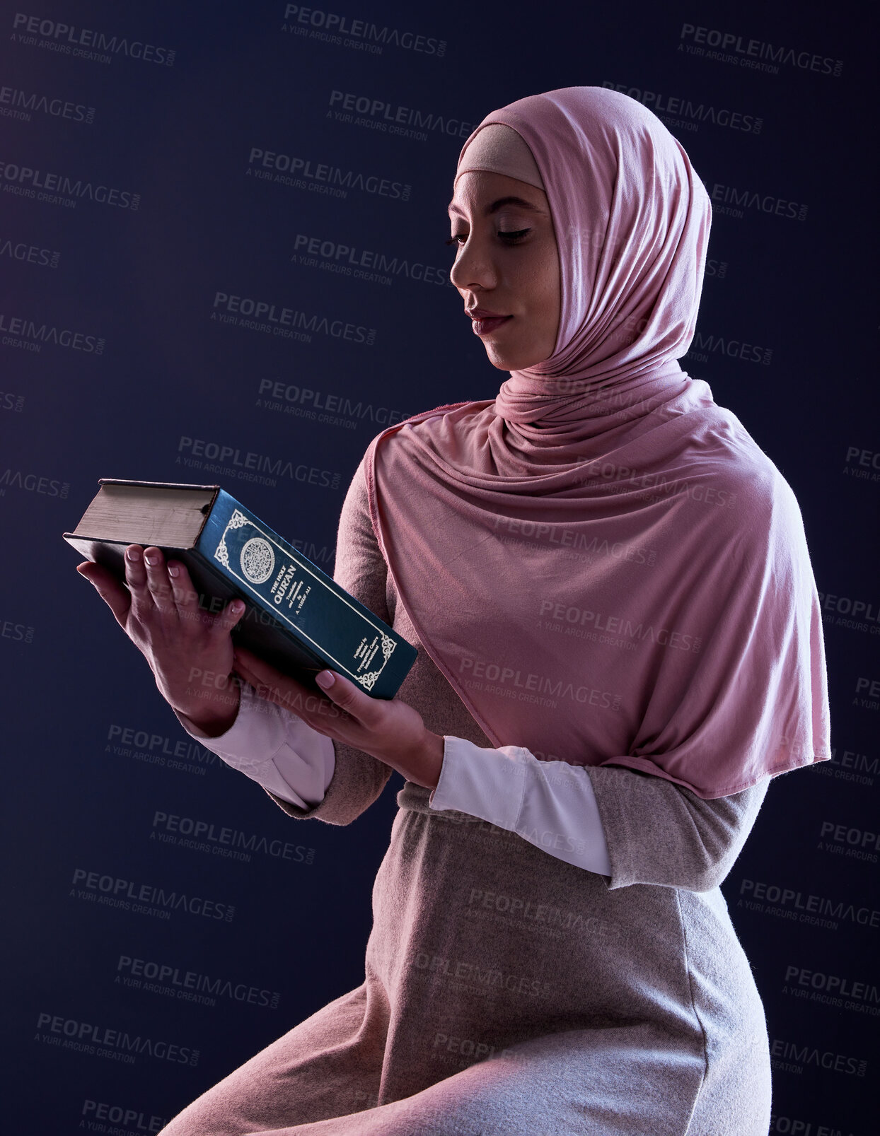 Buy stock photo Quran, faith and muslim woman reading in a studio with traditional clothes and hijab. Serious, religion and young islamic female person studying the holy Arabic book isolated by a black background.