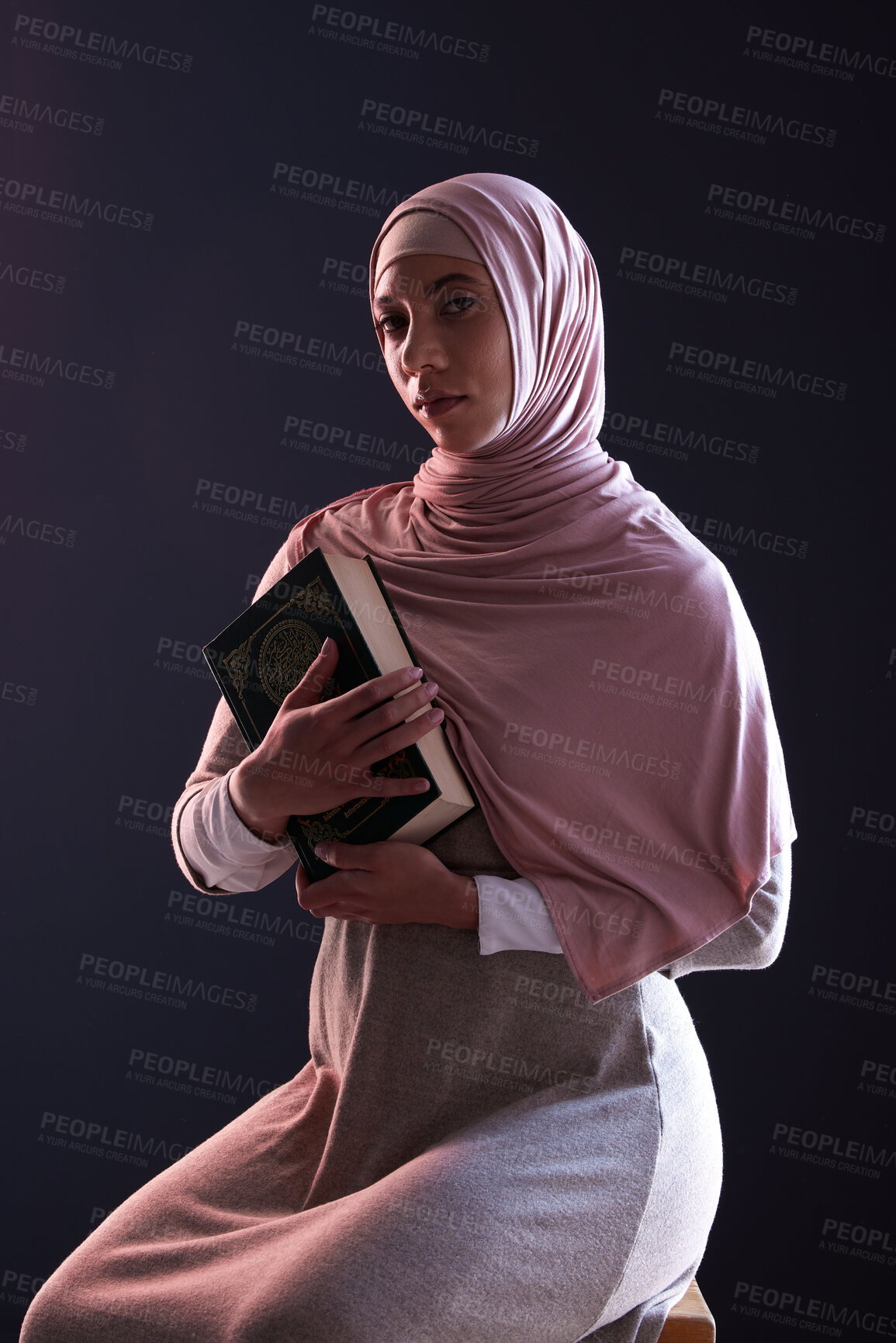 Buy stock photo Quran, religion and portrait of a muslim woman in a studio with traditional clothes and hijab. Serious, faith and young islamic female person with the holy Arabic book isolated by a black background.