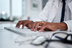 Hands, keyboard and doctor typing at desk for research, healthcare and telehealth on internet in hospital. Computer, fingers and medical professional writing email, planning and work online in clinic