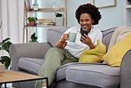 Black woman, coffee and smartphone on sofa in living room, social media and reading funny memes. Happy female person relax on couch, cellphone and tea for texting, chat app and download mobile games 