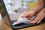 Woman, hands and cleaning laptop for hygiene, disinfection or germ and bacteria removal on wooden desk. Closeup of female person, maid or cleaner wiping computer for sanitizing on table at home