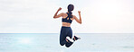 Back, freedom and fitness woman jump at the beach with celebration after running, training or workout success in nature. Exercise, jumping and behind female at the sea celebrating goal milestone