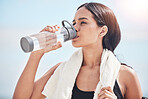 Woman, runner and drinking water after fitness, training and wellness routine outdoor on blue sky background. Workout hydration and female thirsty after intense cardio, running and body exercise