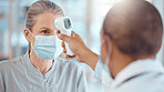 Woman in face mask, doctor and thermometer in office for covid test, safety and healthcare in hospital consultation. Temperature check, corona and patient at clinic with medical professional for exam