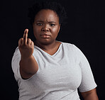 Portrait, anger and black woman with middle finger, opinion and angry expression on a black studio background. Face, female person and African model with hate sign, rude and frustrated with conflict