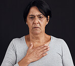 Fear, senior and a woman with a heart attack on a black background with healthcare anxiety. Emergency, sad and an elderly person feeling chest for pain, sick or medical scare isolated on a backdrop