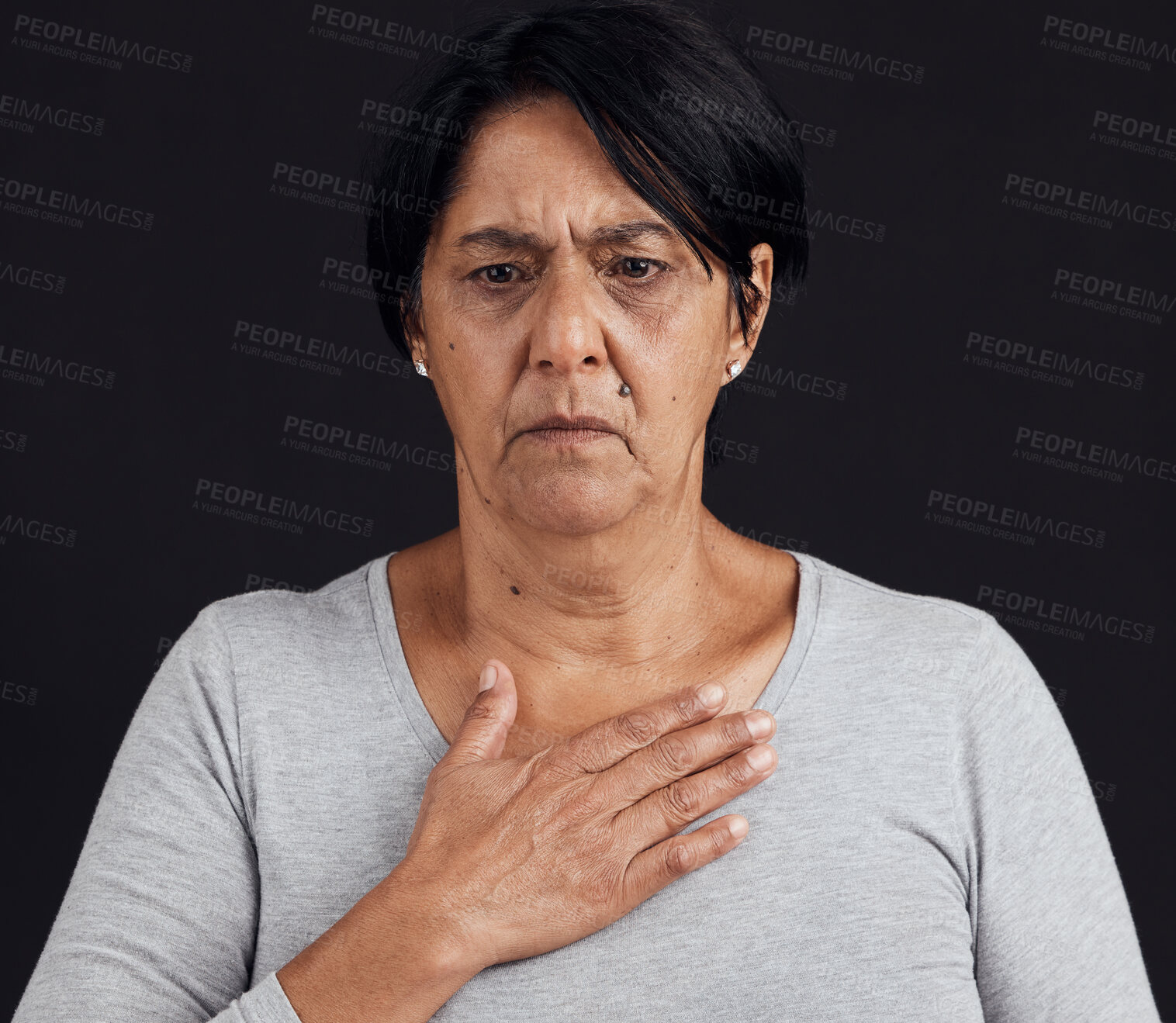 Buy stock photo Fear, senior and a woman with a heart attack on a black background with healthcare anxiety. Emergency, sad and an elderly person feeling chest for pain, sick or medical scare isolated on a backdrop