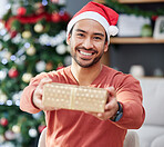 Christmas, portrait and asian man with gift giving in his home for celebration, fun and holiday with a smile. Happy, face and Japanese male with present box offer in a living room for festive event