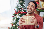 Christmas, surprise and asian man with gift in his home happy, excited and having fun celebrating holiday. Hand holding, box and Japanese male with present in a living room at December party or event