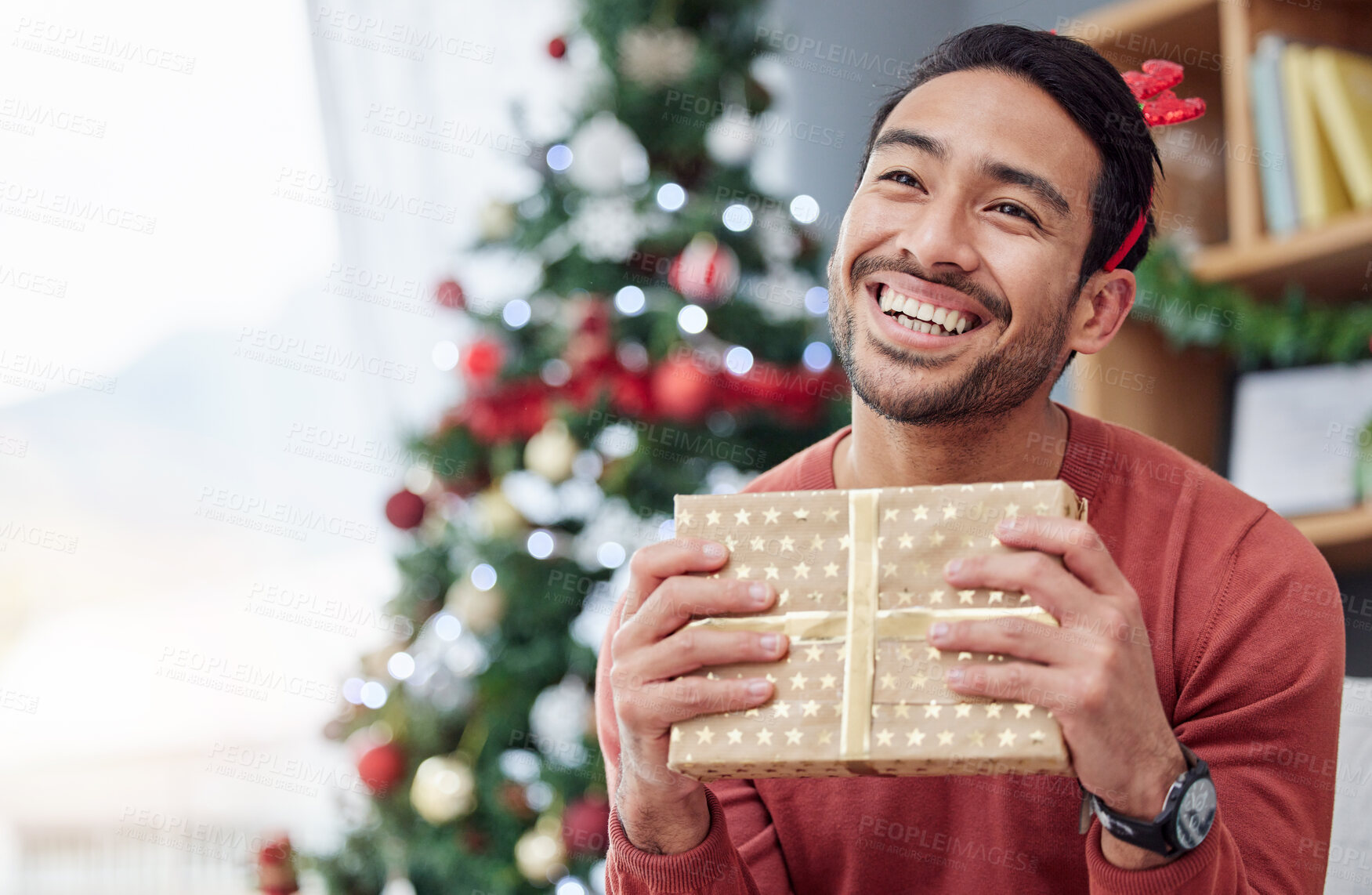 Buy stock photo Christmas, surprise and asian man with gift in his home happy, excited and having fun celebrating holiday. Hand holding, box and Japanese male with present in a living room at December party or event