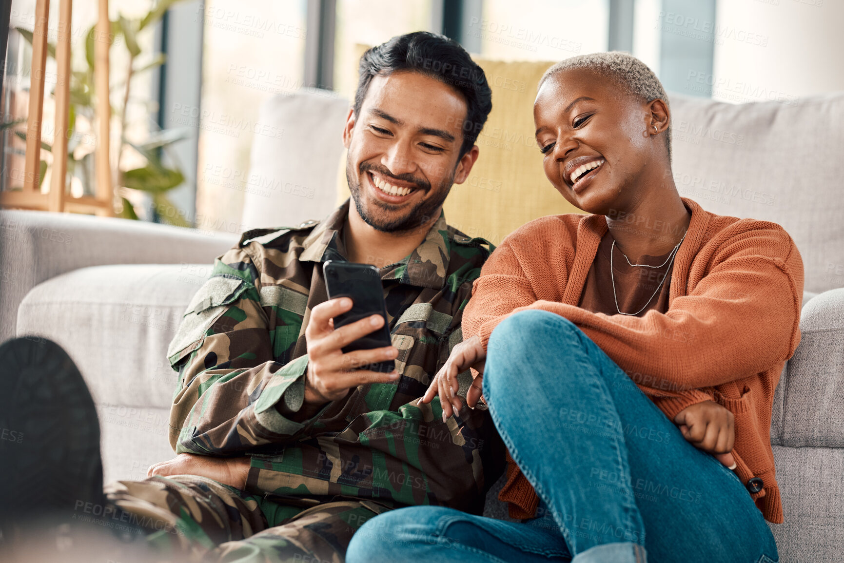 Buy stock photo Army man, interracial couple and return with phone meme at home with laugh and video streaming. Lounge, young people and mobile scroll together in a house sitting on a lounge ground with soldier 