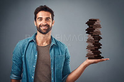 Chocolate, candy and happy with portrait of man in studio for diet, sweets and sugar. Cocoa, food and confectionery with face of person and treat on grey background for unhealthy and snack