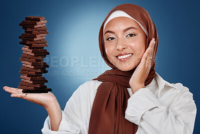 Chocolate, candy and smile with portrait of muslim woman in studio for diet, sweets and sugar. Cocoa, food and confectionery with face of person and treat on blue background for unhealthy and snack
