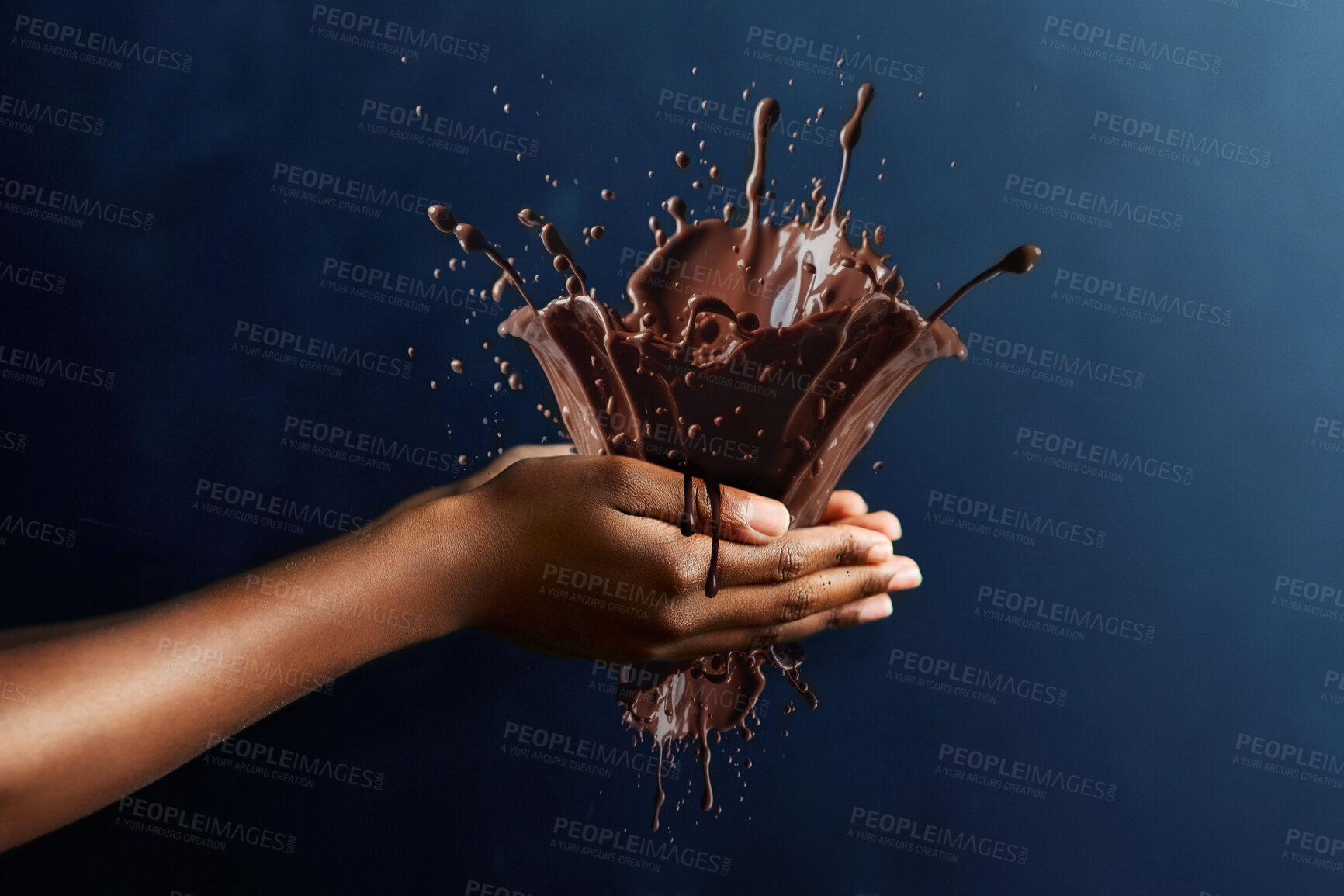 Buy stock photo Chocolate, splash and candy with hand of person in studio for cocoa, dessert and sugar. Confectionary, sweets and treat with closeup of model and on blue background for movement, ingredients and drop