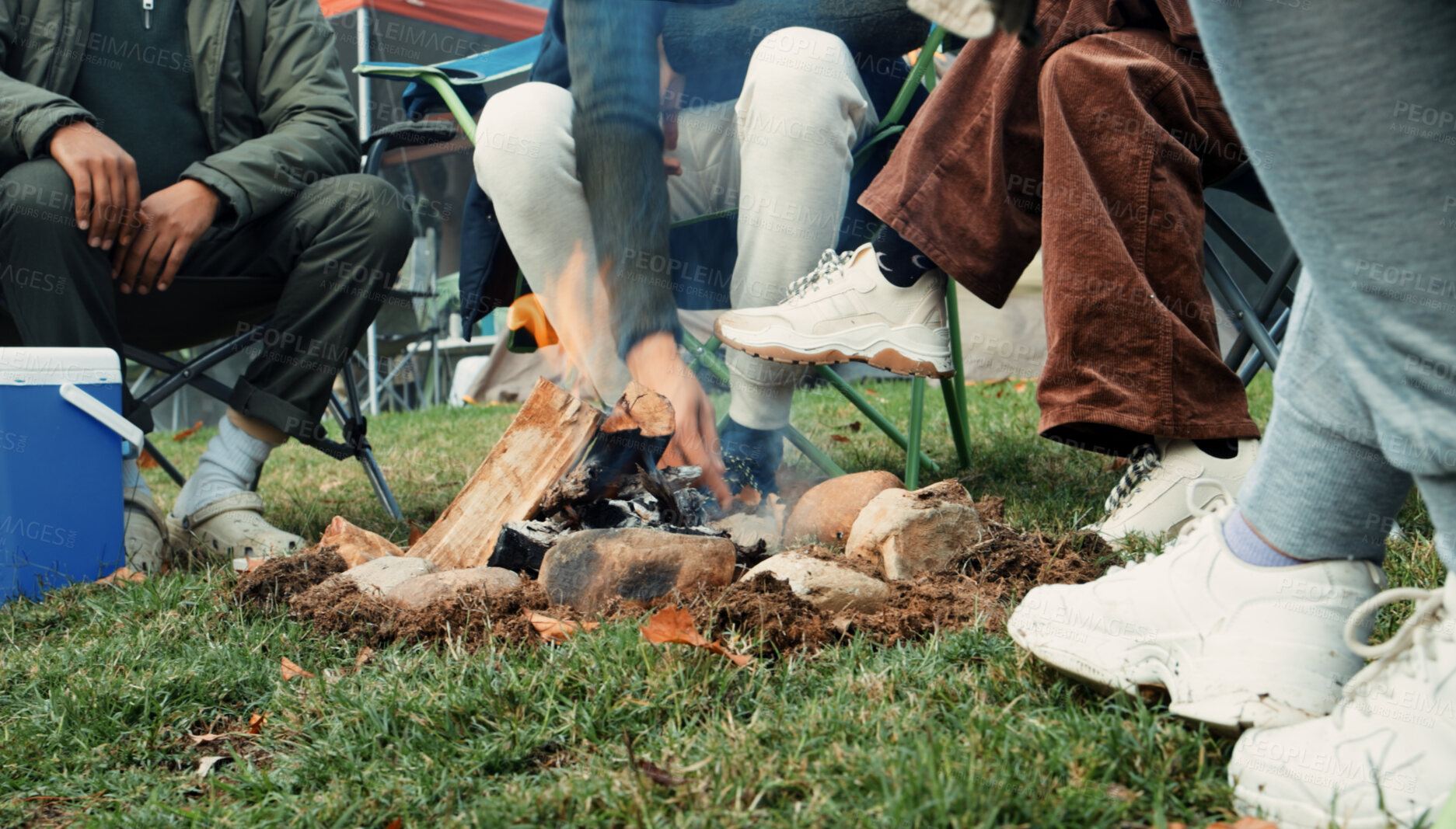 Buy stock photo Feet, friends camping at fire in nature and relax in forest together at bonfire on winter holiday. Campfire, adventure and group of people bonding on outdoor vacation, woods and morning conversation.