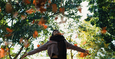 Woman, autumn and throwing leaves outdoor in a park with trees, freedom and fun in nature. Happy and excited person in warm clothes while playful on an adventure, travel or holiday in fall season