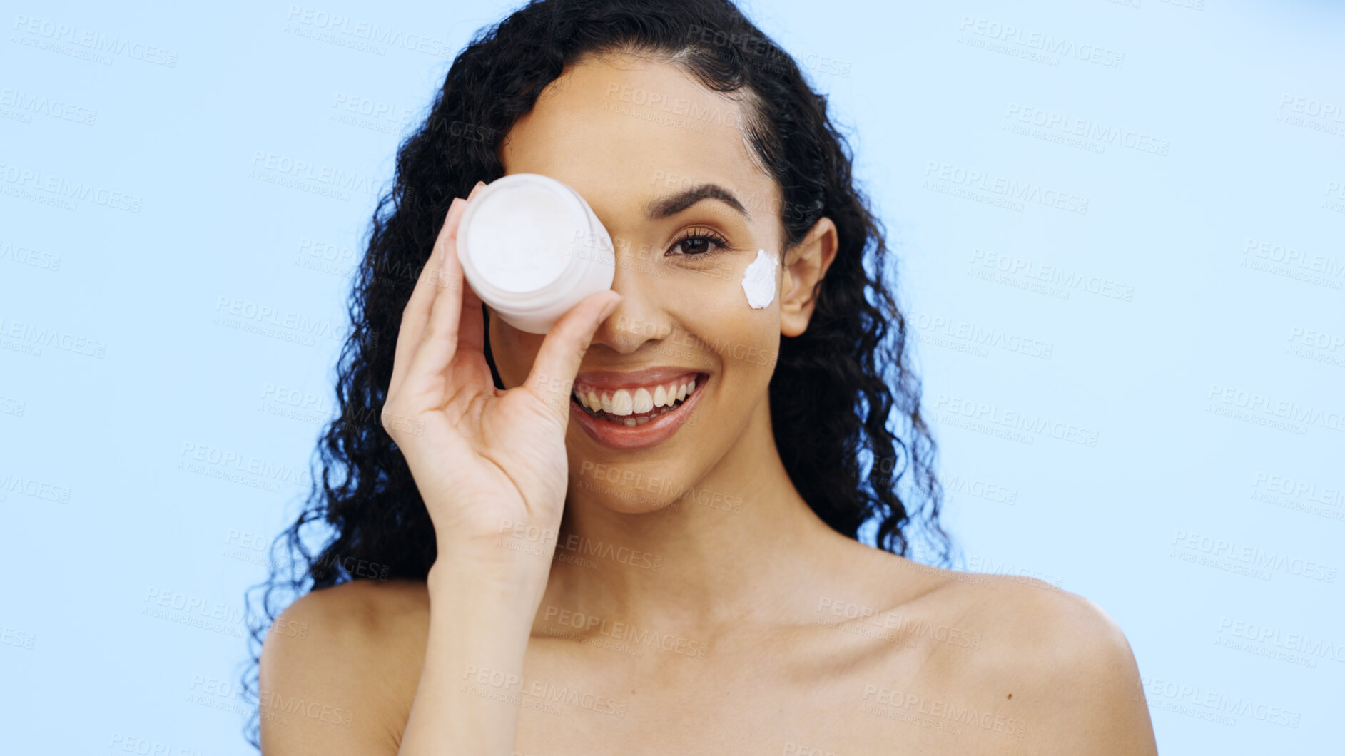 Buy stock photo Face, cream jar and beauty of woman, cosmetics and smile on blue background. Facial lotion, skincare and portrait of happy studio model with container for shine, natural wellness and aesthetic makeup