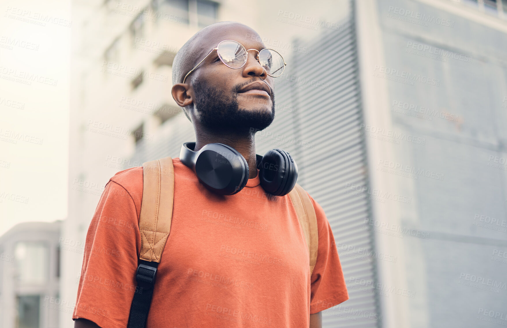 Buy stock photo Black man, student and walking outdoor on a city street while thinking of music and freedom. A serious African person with a backpack on an urban road with casual style and fashion for travel