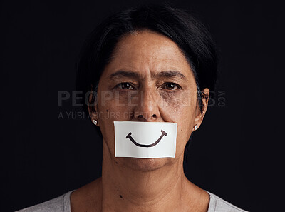 Buy stock photo Portrait, fake smile or abuse and a mature woman in studio on a dark background with an expression. Depression, anxiety and mental health with a female person looking brave to hide her emotions