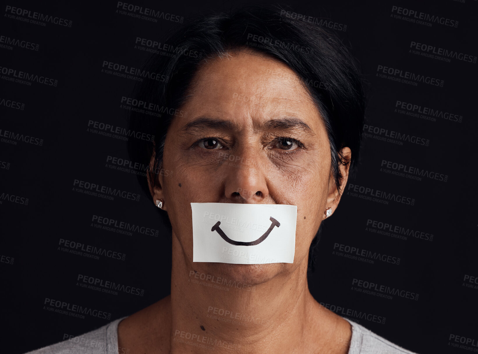 Buy stock photo Portrait, fake smile or abuse and a mature woman in studio on a dark background with an expression. Depression, anxiety and mental health with a female person looking brave to hide her emotions