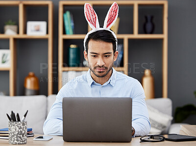 Buy stock photo Laptop, bunny ears and business man for Easter in office with decoration for celebration, event and party. Corporate, focus and Asian male person on computer at desk with rabbit headband for holiday