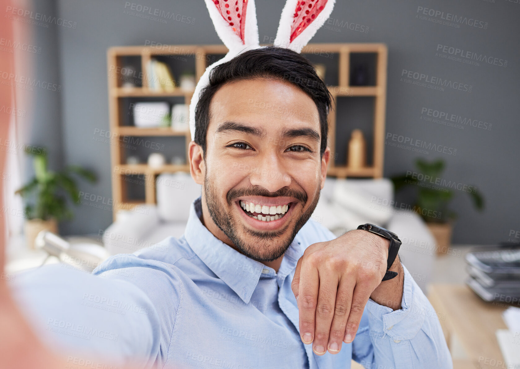 Buy stock photo Bunny ears, holiday and remote work selfie with a man and social media with creative job. Celebration, happy face and male person from Spain feeling silly and goofy with comedy easter hat at home