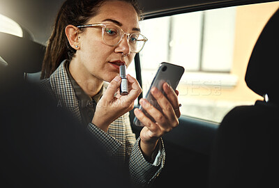 Buy stock photo Phone, lipstick and a business woman in a car to travel in the city for work while multitasking. Face, mobile and makeup with a young female employee in a taxi or cab as a passenger for transport